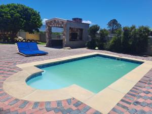 a swimming pool with two blue chairs and a house at Elim self catering in Fisherhaven