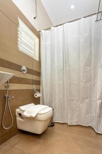 a bathroom with a shower curtain and a toilet at ESAA Airport Hotel Kochi in Cochin