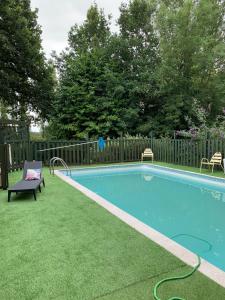 una piscina con un banco junto a una valla en La maison de l'étang en Ploërdut