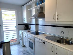 una cocina con armarios blancos y fregadero en NPG429 - Holiday Beach House on the Golf Course, en Huelva