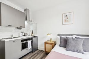 a bedroom with a bed and a kitchen at Sutherland Apartments in London