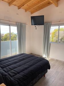 Un dormitorio con una cama y un televisor de pantalla plana. en Bruma Mia, en San Clemente del Tuyú