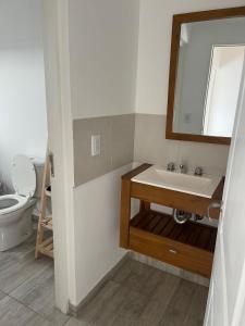 Un baño con lavabo, inodoro y espejo. en Bruma Mia, en San Clemente del Tuyú