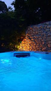 a large blue swimming pool with a stone wall at Apartments Neppa in Postira