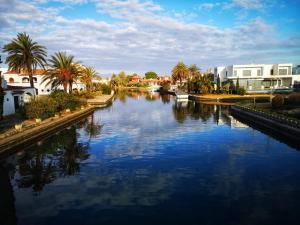 une rivière avec des palmiers et des bâtiments dans une ville dans l'établissement LEON INMO Apartment Oasis - 10022, à Empuriabrava