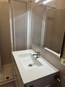 W łazience znajduje się biała umywalka i lustro. w obiekcie Appartamento Porto Azzurro 5/6 beds w mieście Porto Azzurro