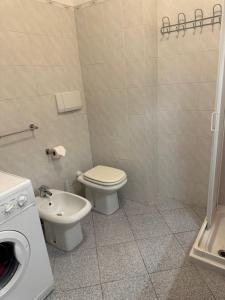 a bathroom with a toilet and a sink and a washing machine at Appartamento Porto Azzurro 5/6 beds in Porto Azzurro