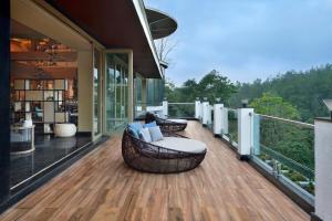 Coorg Marriott Resort & Spa في ماديكيري: السطح مع أريكة وكراسي على المنزل