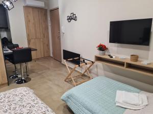 un soggiorno con TV, sedia e tavolo di Fay's luxury loft a Volos