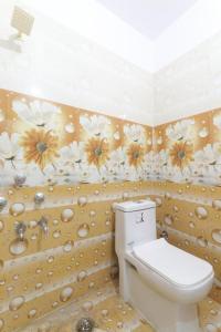 a bathroom with a toilet and flowers on the wall at Hotel Atithi Satkar , Gobarsahi in Muzaffarpur