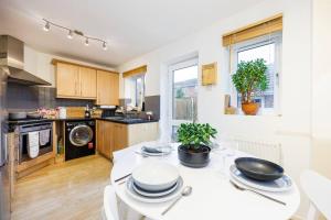 a kitchen with a white table with plates on it at Stylish 2-Bed East London Home Contractors Parking Sleeps 5 Near ExCeL London in London