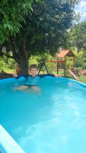 a young boy in a swimming pool with a playground at Condado Rosa & Duarte in Piumhi