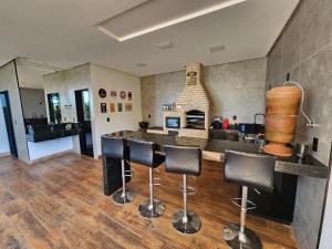 a kitchen with a bar with chairs and a fireplace at Condado Rosa & Duarte in Piumhi