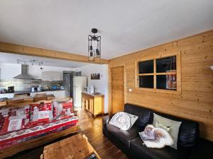 ein Wohnzimmer mit einem Sofa und einer Küche in der Unterkunft Appartement cosy, esprit montagne, au cœur du village in Chapelle-des-Bois