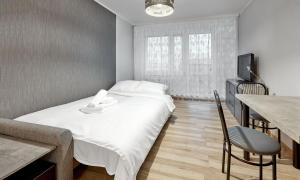 1 dormitorio con cama, mesa y TV en Pod Lipami Standard Studio, en Poznan