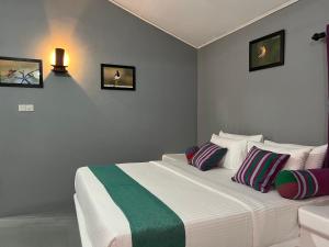 a bedroom with a white bed with colorful pillows at Kingfisher Beach Resort -Yala in Kirinda