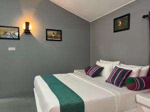 a bedroom with a white bed with colorful pillows at Kingfisher Beach Resort-Yala in Kirinda