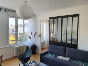 a living room with a blue couch and some windows at Suite Forum Vue Imprenable in Reims