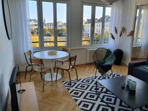 Suite Forum Vue Imprenable في رانس: غرفة معيشة مع طاولة وكراسي ونوافذ