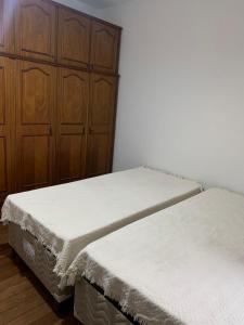 two beds in a room with a wooden cabinet at Quartos em casa no Clelia Bernardes in Viçosa