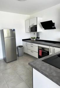 a kitchen with a stainless steel refrigerator and white cabinets at Villa Pacifico avec spa in Baillif