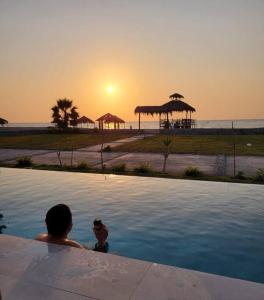 um homem a tirar uma foto do pôr-do-sol numa piscina em HERMOSA CASA CON PISCINA FRENTE AL MAR - PRIMERA FILA em Chincha Baja