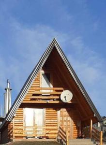 una grande casa in legno con un orologio sopra di Planinski Mir a Pale