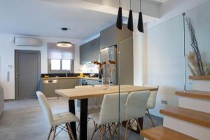 cocina con mesa de madera y sillas blancas en Aloft Luxury Villas with heated pool and sea view, en Apolpaina