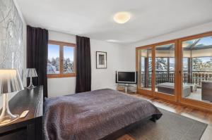 a bedroom with a bed and a television and a balcony at Magnificent flat in Crans-Montana - 856 in Crans-Montana