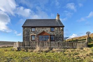a stone house on a hill with a wooden fence at Finest Retreats - Llechwedd Mawr in Talybont