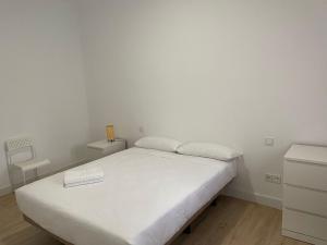 um quarto com uma cama branca com um livro em U4 Apartamento a estrenar, centro Madrid em Madrid