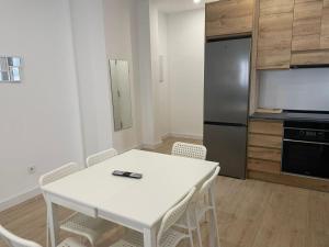 uma cozinha com uma mesa e cadeiras brancas e um frigorífico em U4 Apartamento a estrenar, centro Madrid em Madrid
