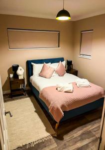 a bedroom with a bed with pink pillows at Chic Coastal Hideaway: 2-BR Gem Southend Stays in Southend-on-Sea