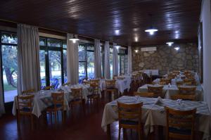 ein Esszimmer mit Tischen und Stühlen mit weißen Tischeinstellungen in der Unterkunft Hotel Posta Arroyito in Arroyito Challacó