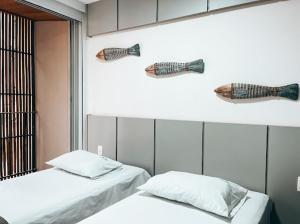 duas camas num quarto com cabeças de peixe na parede em Residencial Bambu, frente mar em Ubatuba
