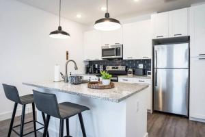 una cocina con armarios blancos y una barra con sillas en Swanky Atlanta Apartment en Atlanta