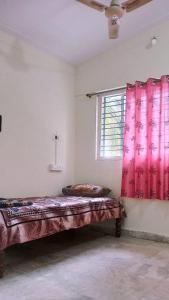 a bed in a room with red curtains and a window at Funky Buddha Hostel in Mysore