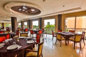 uma sala de jantar com mesas, cadeiras e janelas em Complexe El Bassatine em Beni Mellal