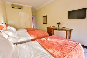 a bedroom with two beds and a television on the wall at Complexe El Bassatine in Beni Mellal