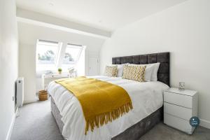 a white bedroom with a large bed with a yellow blanket at Days Away - Luxury holiday home in Radipole