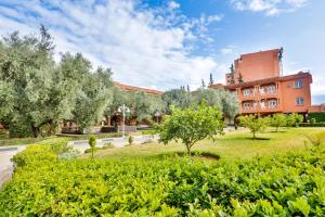 un parque con árboles y un edificio al fondo en Complexe El Bassatine, en Beni Mellal