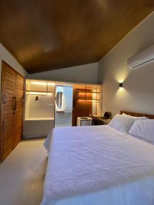 a bedroom with a large white bed and a kitchen at CHALE VILAALICE in Monte das Gameleiras