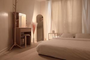 ein weißes Schlafzimmer mit einem Bett und einem Spiegel in der Unterkunft Seoul Sensibility B&B House in Seoul