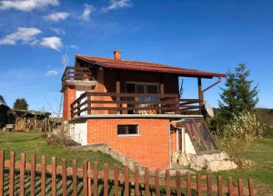 a brick house with a fence in front of it at Mountain resort house-Planinska vikendica in Han Pijesak