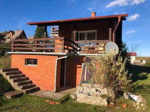 a small brick house with a porch and stairs at Mountain resort house-Planinska vikendica in Han Pijesak