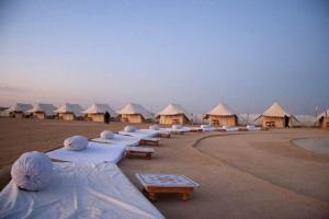 een rij strandhutten met tafels en parasols bij Explore Overnight Desert Safari Jaisalmer in Jaisalmer