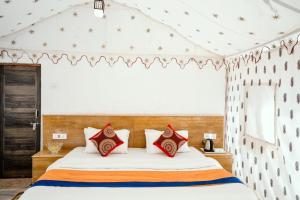 een slaapkamer met een groot bed met rode kussens bij Explore Overnight Desert Safari Jaisalmer in Jaisalmer