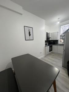 a white kitchen with a table and a refrigerator at London Homes in London