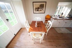 a kitchen with a wooden table and white chairs at The Lodge: Adorable, Romantic Thatched Cottage in Freshwater +10 photos