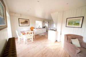 a living room with a table and chairs and a kitchen at The Lodge: Adorable, Romantic Thatched Cottage in Freshwater